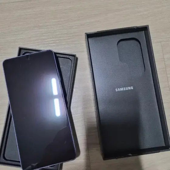 Eingeschaltetes Galaxy S26 Ultra in der Verpackung, daneben der Deckel